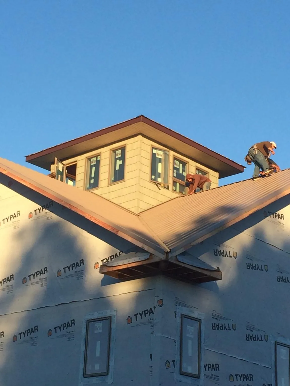 Roofers working around a rooftop cupola on a new metal roof at sunset — Roof Waterproofing in Stillwater by Roofing Brothers